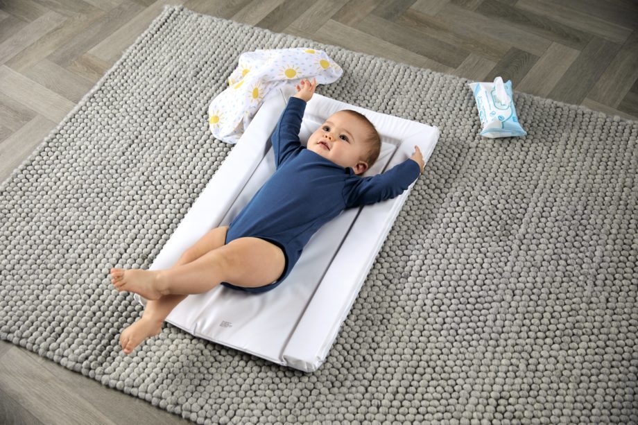 Baby laying on a changing mat in a blue babygrow