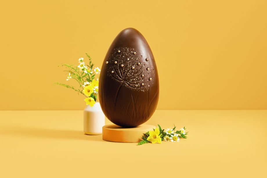 Milk Chocolate egg with a floral design on a plain yellow backdrop.