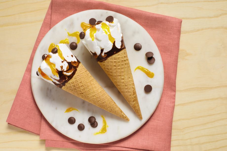 Ice cream cones with a yellow fondant drizzle, on a place with a pink napkin
