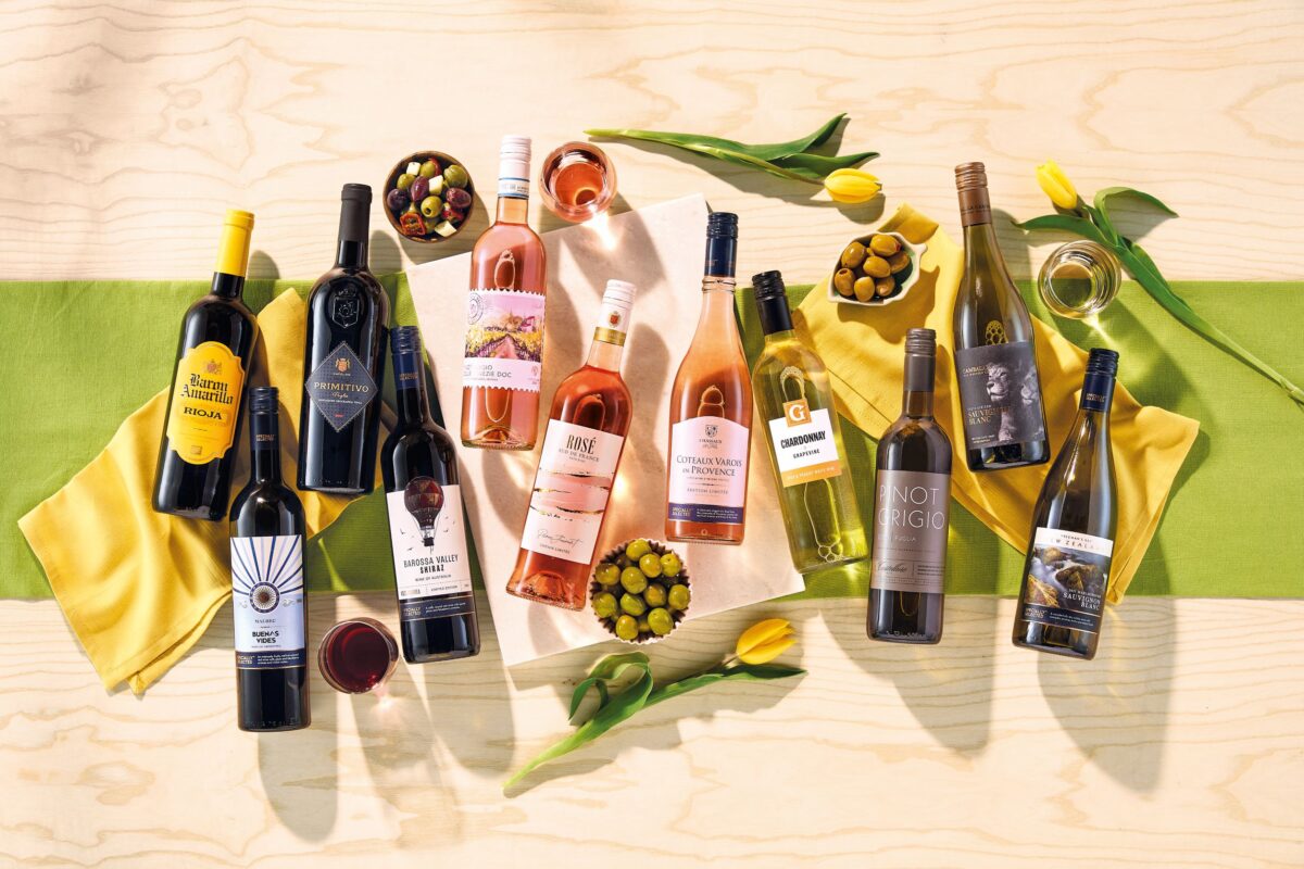 Aldi's range of Spring Summer Wines laid flat on a green runner with botanicals