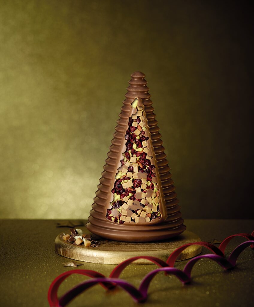 Front loaded christmas tree made from milk chocolate. On gold plate in front of gold background.