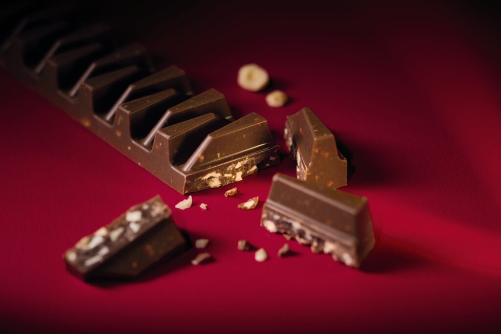 Chocolate bar with nougat pieces within it on red background.