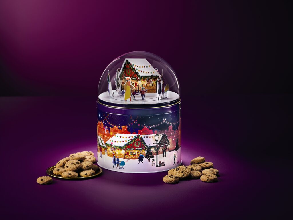 Musical biscuit tin with glass dome on top. Christmas night time scene within the dome including ice skaters and a cottage.