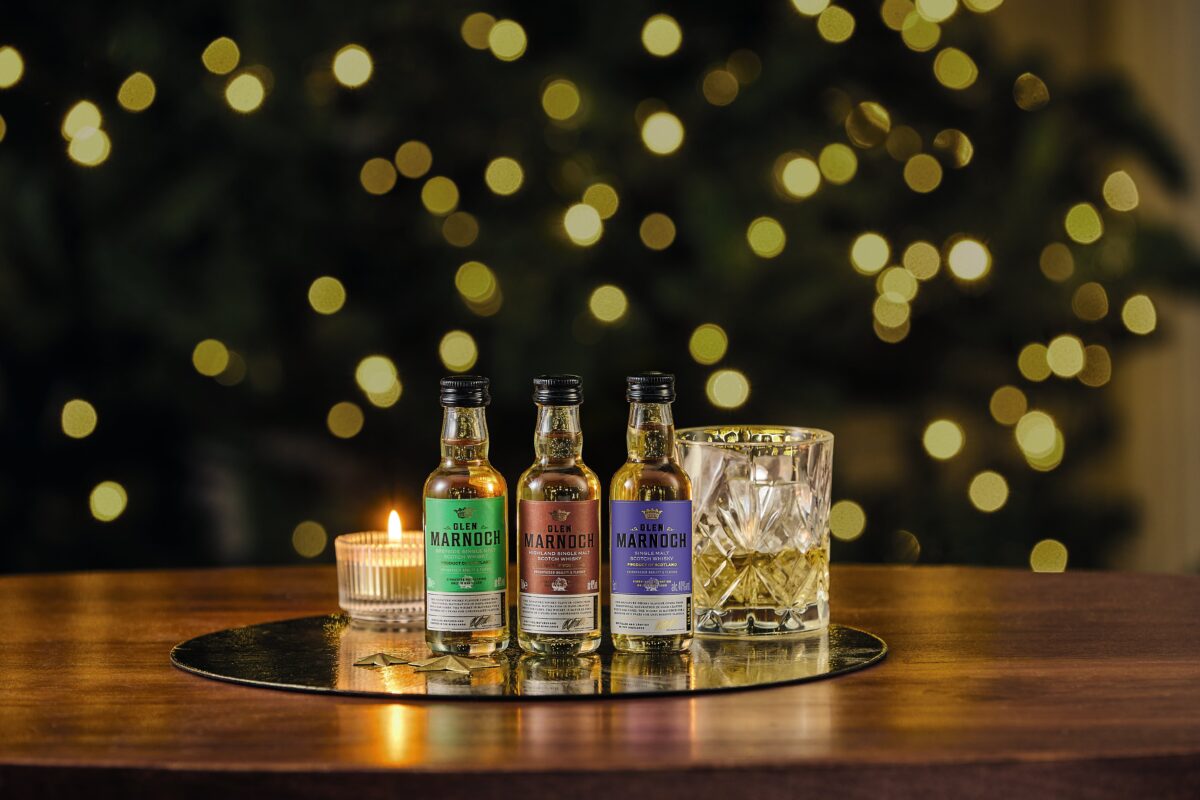 Three Glen Marnoch bottles placed with a candle and a glass